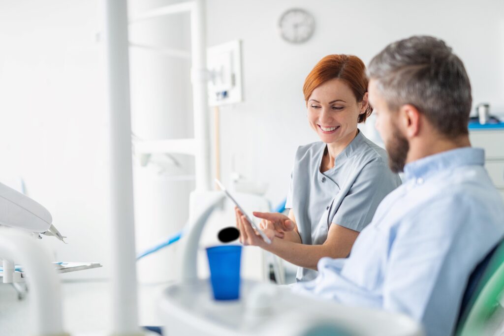 Smiling dentist showing patient information on tablet